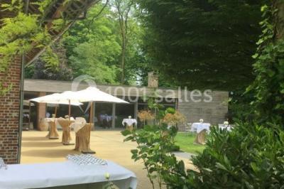 Table élégamment dressée avec nappes blanches, vaisselle raffinée, bougies allumées et décoration florale.