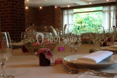 Table élégamment dressée avec nappes blanches, vaisselle raffinée, bougies allumées et décoration florale.