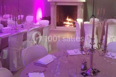 Table élégamment dressée avec nappes blanches, vaisselle raffinée, bougies allumées et décoration florale.