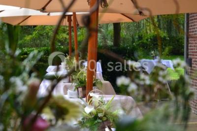 Table élégamment dressée avec nappes blanches, vaisselle raffinée, bougies allumées et décoration florale.