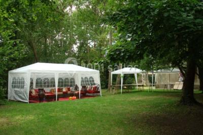 Deux lits simples avec couvertures vertes dans une chambre mansardée aux poutres apparentes et murs en plâtre.