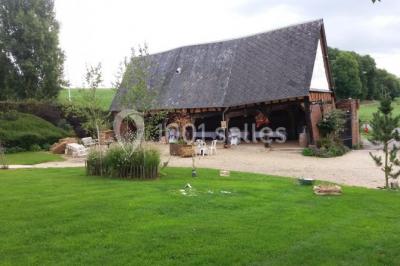 Jardin avec bancs, tables en bois et un pigeonnier en arrière-plan sous un ciel nuageux.