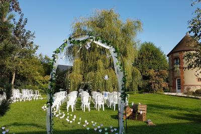 Jardin avec bancs, tables en bois et un pigeonnier en arrière-plan sous un ciel nuageux.