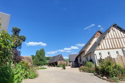 Jardin avec bancs, tables en bois et un pigeonnier en arrière-plan sous un ciel nuageux.