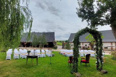 Jardin avec bancs, tables en bois et un pigeonnier en arrière-plan sous un ciel nuageux.