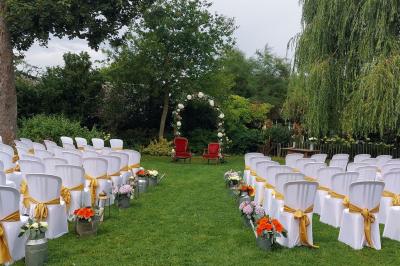 Jardin avec bancs, tables en bois et un pigeonnier en arrière-plan sous un ciel nuageux.