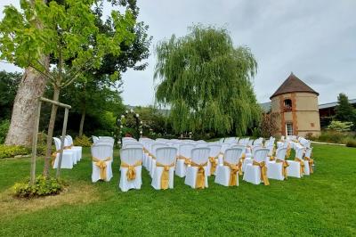 Jardin avec bancs, tables en bois et un pigeonnier en arrière-plan sous un ciel nuageux.