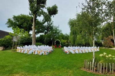 Jardin avec bancs, tables en bois et un pigeonnier en arrière-plan sous un ciel nuageux.