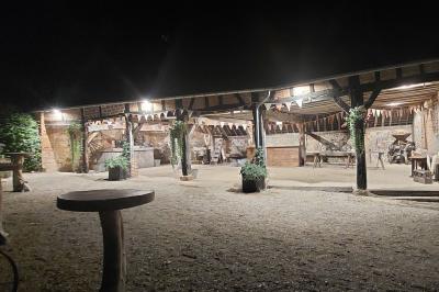 Jardin avec bancs, tables en bois et un pigeonnier en arrière-plan sous un ciel nuageux.
