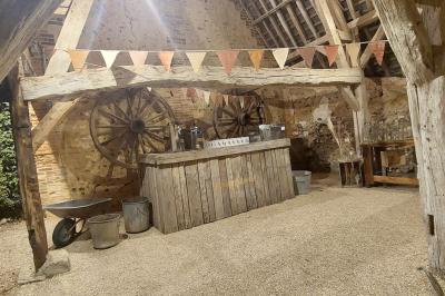 Jardin avec bancs, tables en bois et un pigeonnier en arrière-plan sous un ciel nuageux.