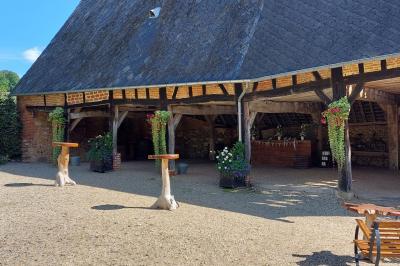 Jardin avec bancs, tables en bois et un pigeonnier en arrière-plan sous un ciel nuageux.