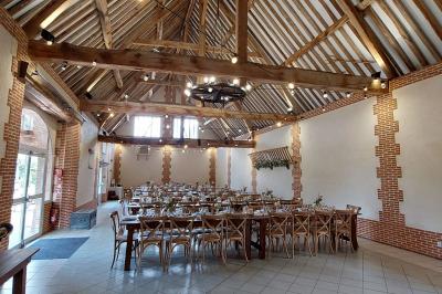 Jardin avec bancs, tables en bois et un pigeonnier en arrière-plan sous un ciel nuageux.