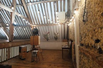 Jardin avec bancs, tables en bois et un pigeonnier en arrière-plan sous un ciel nuageux.