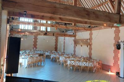 Jardin avec bancs, tables en bois et un pigeonnier en arrière-plan sous un ciel nuageux.