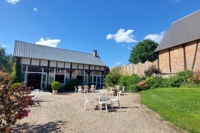 Jardin avec bancs, tables en bois et un pigeonnier en arrière-plan sous un ciel nuageux.