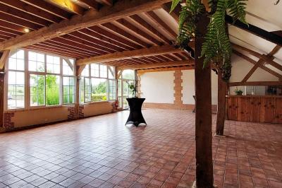 Jardin avec bancs, tables en bois et un pigeonnier en arrière-plan sous un ciel nuageux.