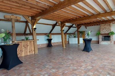 Jardin avec bancs, tables en bois et un pigeonnier en arrière-plan sous un ciel nuageux.