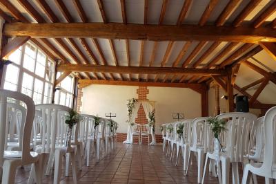 Jardin avec bancs, tables en bois et un pigeonnier en arrière-plan sous un ciel nuageux.