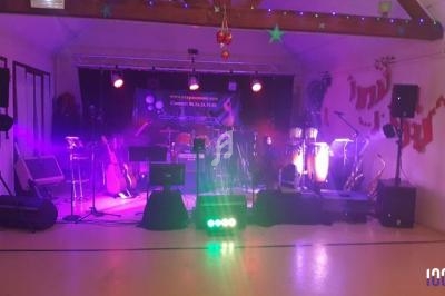 Scène de concert éclairée en violet avec instruments de musique et matériel audio installés dans une salle.