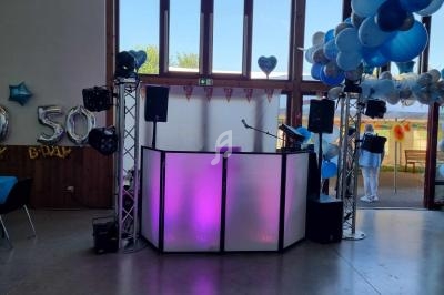Installation de DJ avec éclairage coloré et ballons décoratifs dans une salle de fête lumineuse.