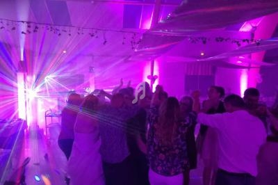Groupe de personnes dansant sous des lumières colorées dans une salle décorée pour une fête.