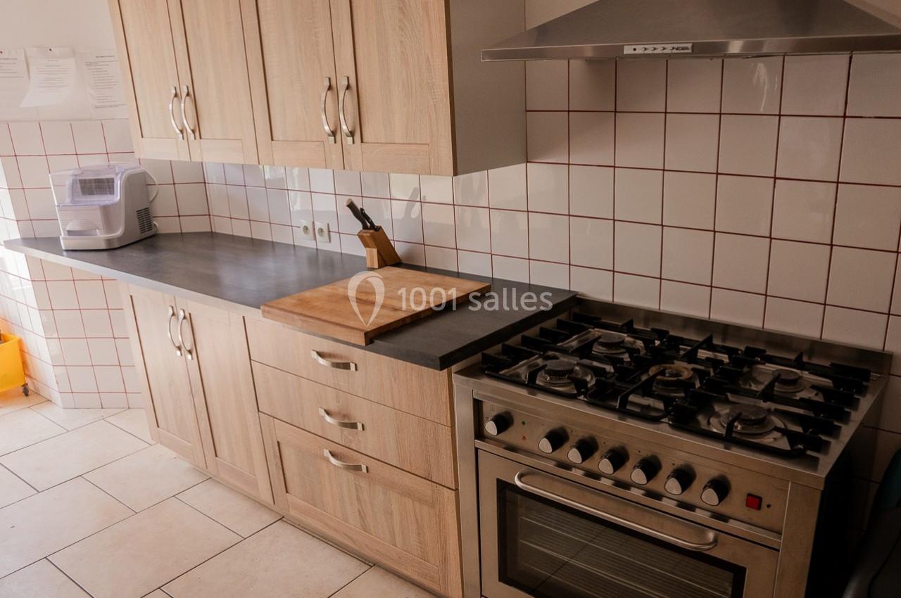 Cuisine équipée avec plan de travail en bois, plaque de cuisson à gaz, four intégré et carrelage mural blanc.