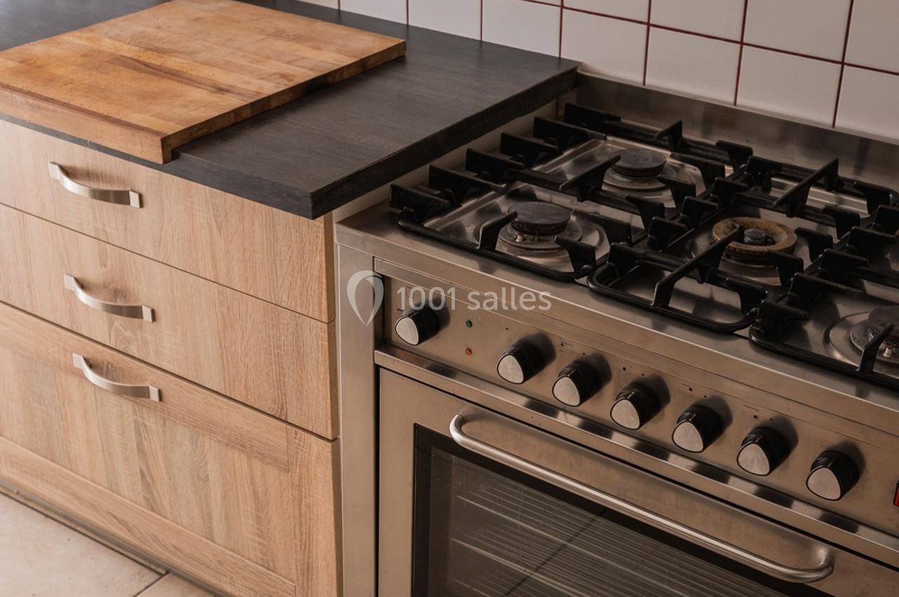 Cuisinière à gaz avec four intégré à côté d'un plan de travail en bois et d'un meuble de rangement.