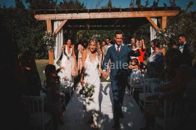 Une mariée lance son bouquet à un groupe de femmes rassemblées dans un jardin lors d'une réception en soirée.