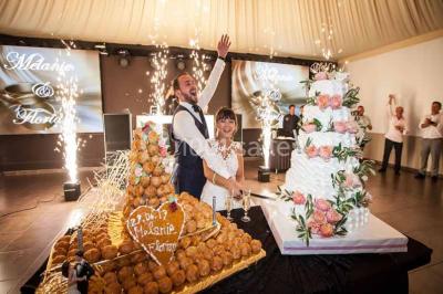 Une mariée lance son bouquet à un groupe de femmes rassemblées dans un jardin lors d'une réception en soirée.