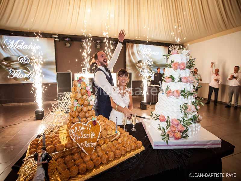 Un couple coupe un gâteau de mariage entouré de décorations festives et de fontaines d'étincelles.
