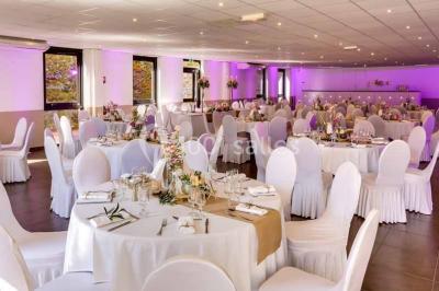 Une mariée lance son bouquet à un groupe de femmes rassemblées dans un jardin lors d'une réception en soirée.