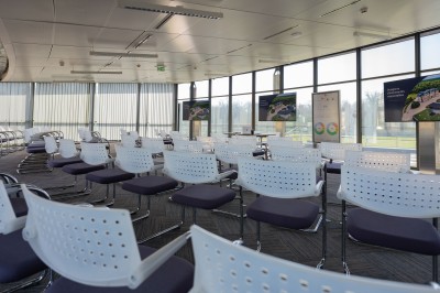 Miniature Location salle Chantilly (Oise) - Les Fontaines #11 Espace de discussion moderne avec fauteuils gris, tables basses noires, plantes et éclairage coloré en arrière-plan.