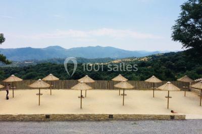 Vue aérienne d'un complexe avec piscine, toboggan aquatique, mini-golf et espaces ombragés entourés de végétation.