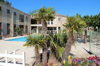 Vue aérienne d'un complexe avec piscine, toboggan aquatique, mini-golf et espaces ombragés entourés de végétation.