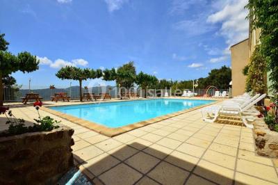 Vue aérienne d'un complexe avec piscine, toboggan aquatique, mini-golf et espaces ombragés entourés de végétation.