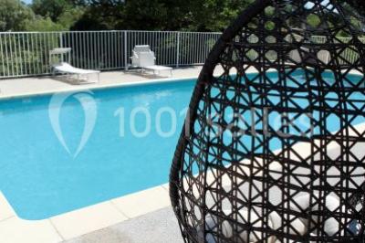 Montagne rocheuse éclairée par une lumière douce, entourée de collines boisées et d'arbres au premier plan.