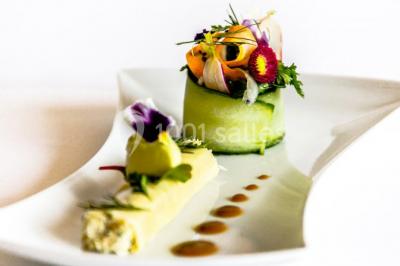 Montagne rocheuse éclairée par une lumière douce, entourée de collines boisées et d'arbres au premier plan.