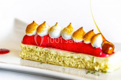 Montagne rocheuse éclairée par une lumière douce, entourée de collines boisées et d'arbres au premier plan.