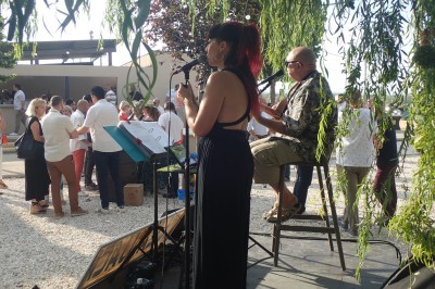 Un duo musical se produit sur une scène intérieure avec guitare et chant, devant un public assis.
