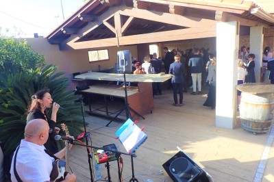 Un duo musical se produit sur une scène intérieure avec guitare et chant, devant un public assis.