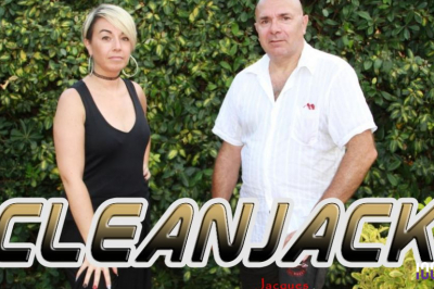 Un homme jouant de la guitare et une femme souriante posent devant des micros à bord d'un bateau.