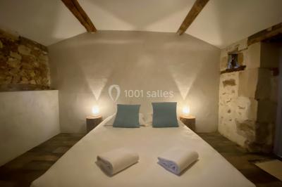 Chemin de gravier menant à une maison en pierre avec toit en tuiles, entourée de verdure et d'une clôture en bois.