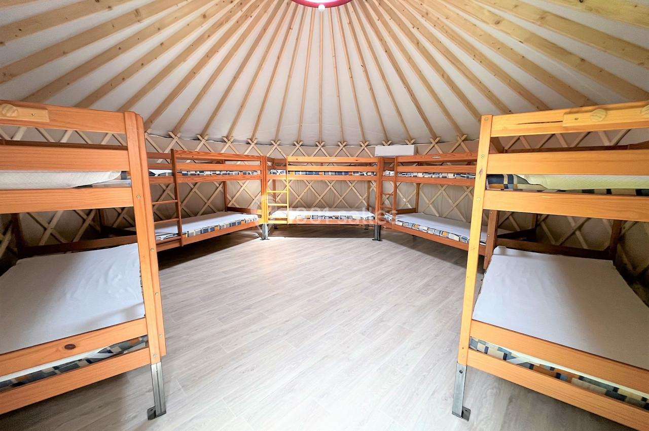 Intérieur d'une yourte avec plusieurs lits superposés en bois disposés en cercle autour de l'espace central.