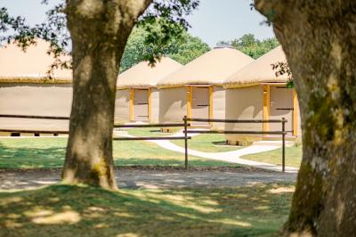 Chemin de gravier menant à une maison en pierre avec toit en tuiles, entourée de verdure et d'une clôture en bois.