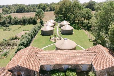 Chemin de gravier menant à une maison en pierre avec toit en tuiles, entourée de verdure et d'une clôture en bois.