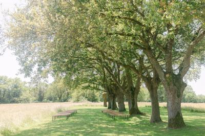 Chemin de gravier menant à une maison en pierre avec toit en tuiles, entourée de verdure et d'une clôture en bois.
