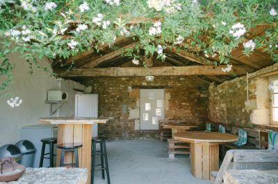 Chemin de gravier menant à une maison en pierre avec toit en tuiles, entourée de verdure et d'une clôture en bois.