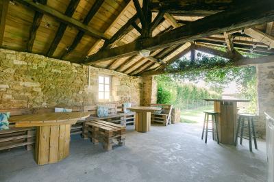 Chemin de gravier menant à une maison en pierre avec toit en tuiles, entourée de verdure et d'une clôture en bois.