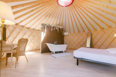 Chemin de gravier menant à une maison en pierre avec toit en tuiles, entourée de verdure et d'une clôture en bois.