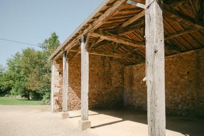 Chemin de gravier menant à une maison en pierre avec toit en tuiles, entourée de verdure et d'une clôture en bois.
